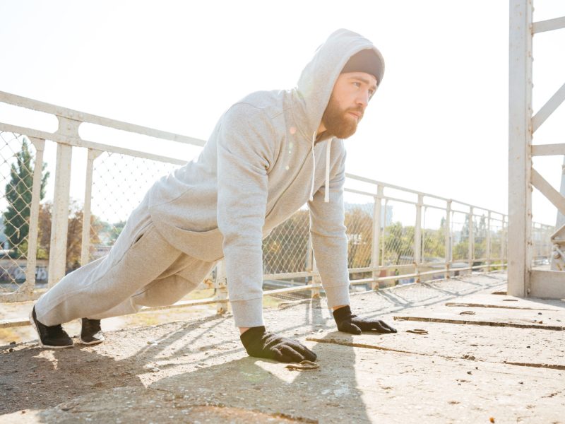 Handsome young fitness man doing push-up exercises outdoors