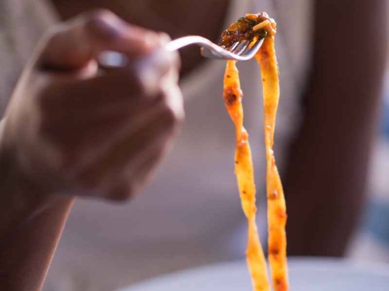 a young African American woman eating pasta